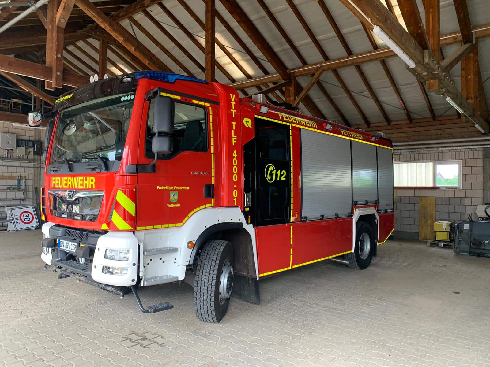 Löschfahrzeug der Freiwilligen Feuerwehr Vettweiß mit gelber Beschriftung und Warnmarkierungen in der Fahrzeughalle
